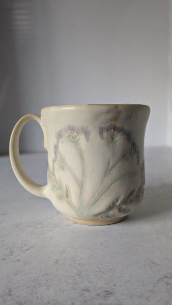 Ceramic mug with leaf design on a white surface