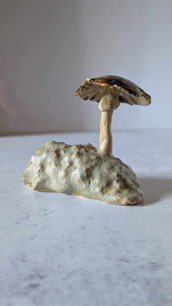 Small ceramic mushroom sculpture on a textured surface