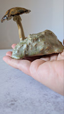 Hand holding a mushroom-shaped object against a neutral background